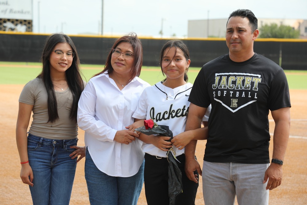 Softball player smiles on field with family